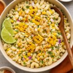 A plate of Elote Pasta Salad with some lime slices